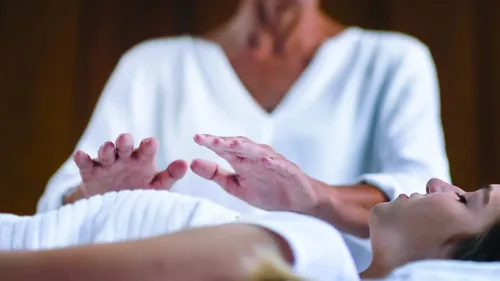 A Reiki practitioner gently placing hands above a client to channel healing energy and promote well-being
